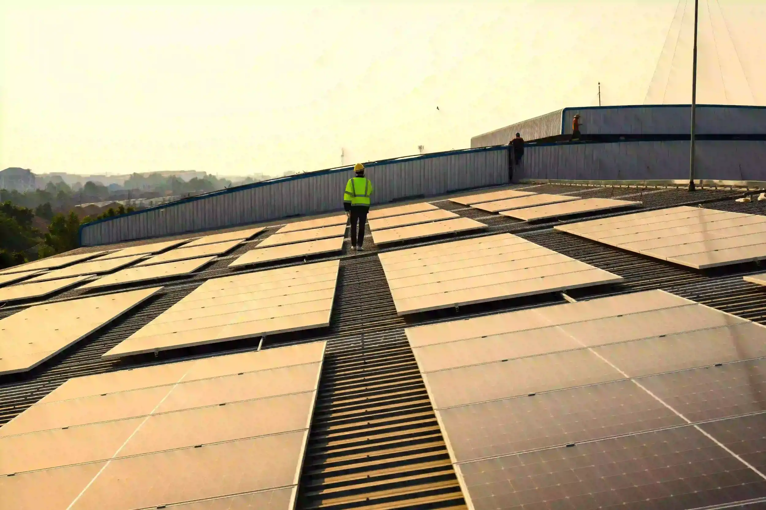 Engineer walking across a large solar panel installation during sunrise, inspecting system performance for National Solar Network.