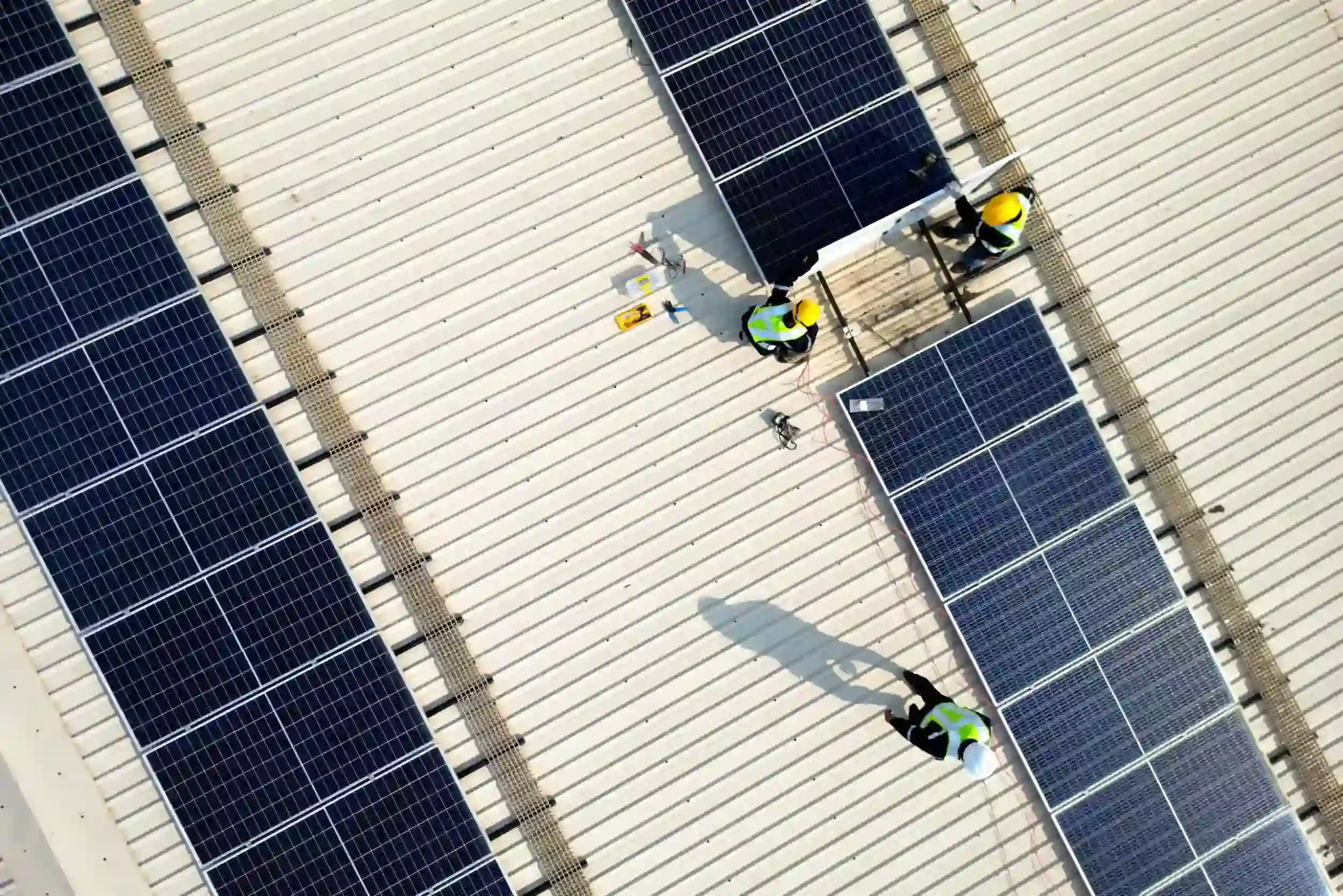 Commercial solar installation workers mounting panels on a large Rockhampton commercial rooftop.