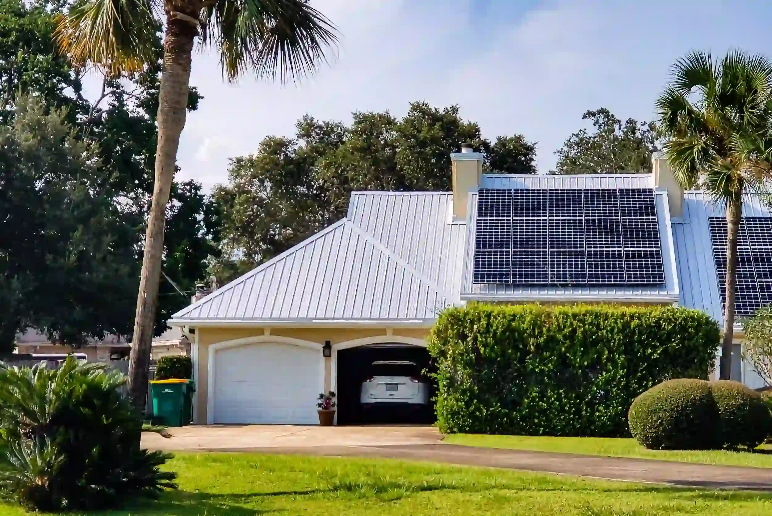 Residential home in Rockhampton featuring rooftop solar panels surrounded by palm trees.