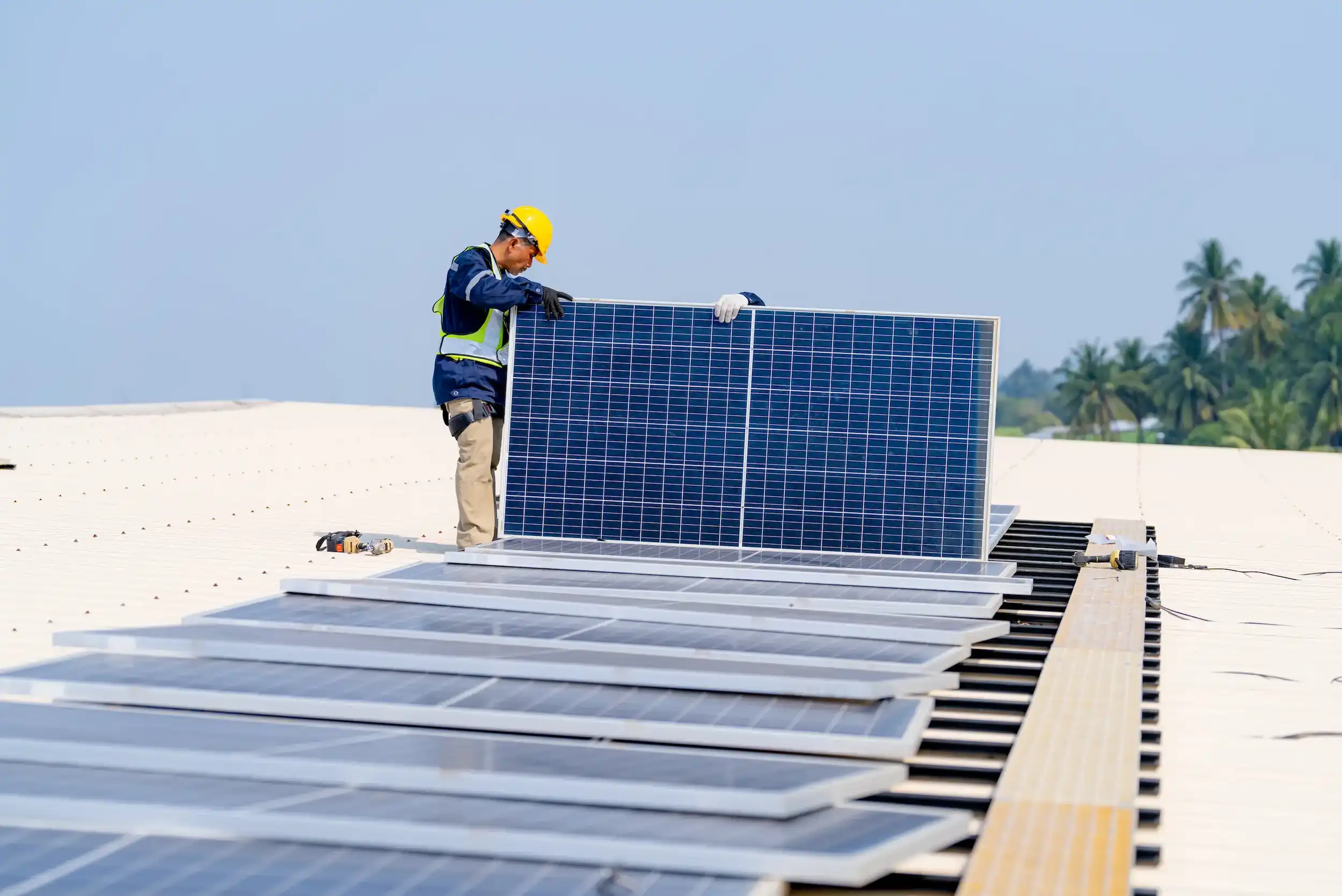 Worker positioning large solar panels on a residential rooftop in Rockhampton.