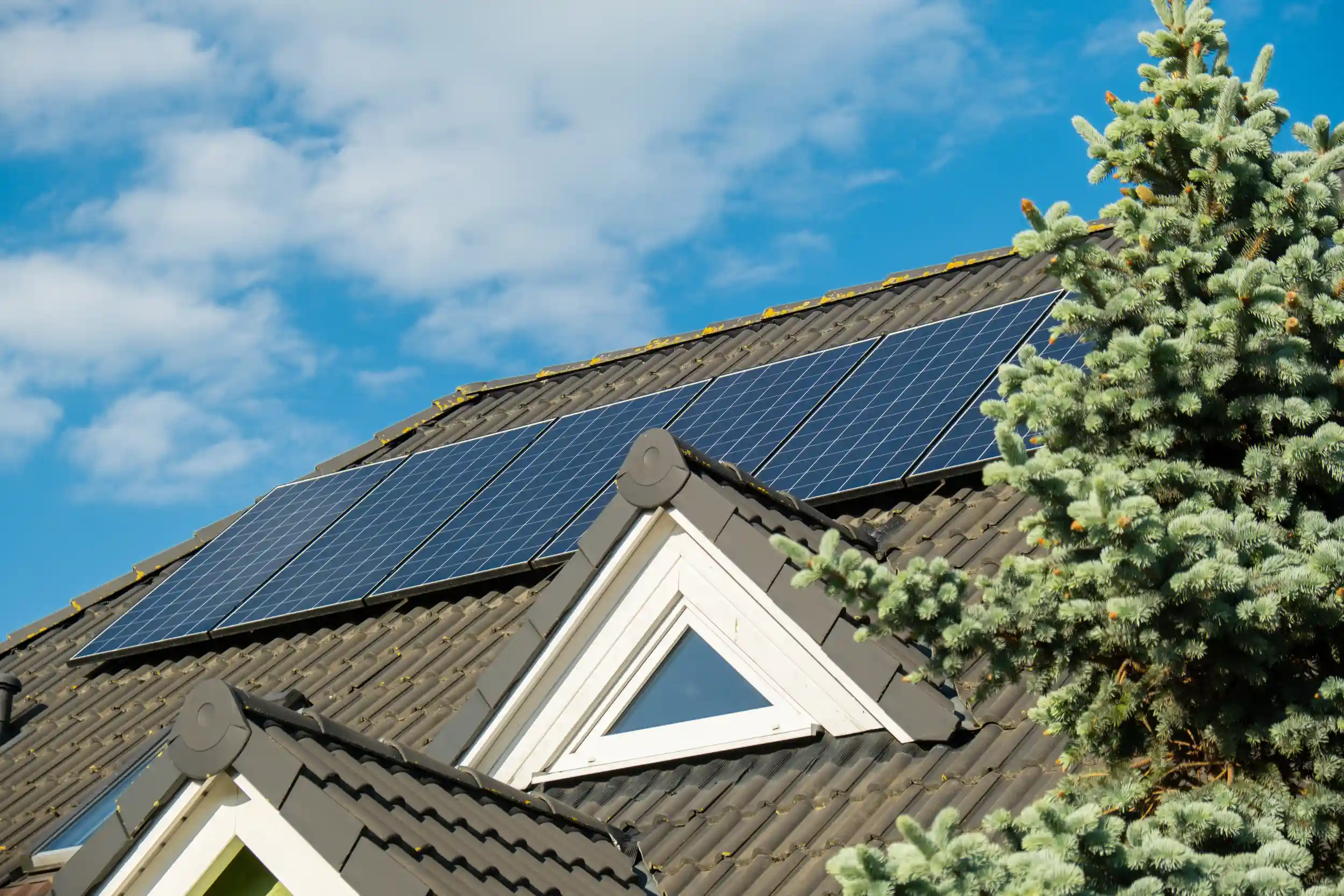 Residential home in Cawarral featuring solar panels installed on a sloped roof surrounded by greenery.